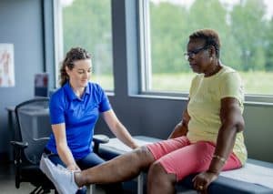 Physical therapist is assessing a woman's knee and leg