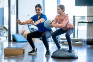 Physical therapist working with a girl balancing on a Bosu ball